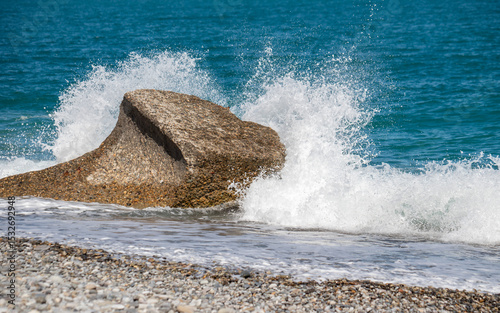 Fototapeta Naklejka Na Ścianę i Meble -  A large rock is in the ocean and the water is splashing around it