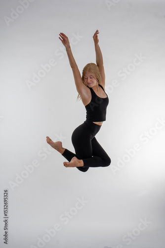 Dancer Toni in the studio dancing Dancer Toni in the studio dancing with motion and light - The image depicts a dancer captured mid-air in a striking pose. They are dressed in a black tank top and bla