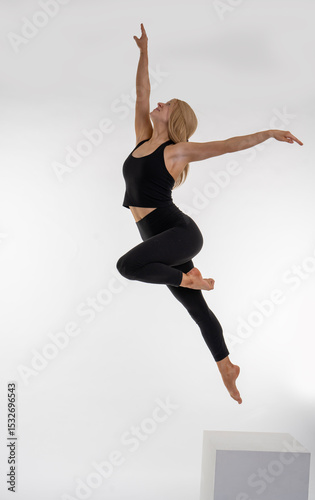 Dancer Toni in the studio dancing Dancer Toni in the studio dancing with motion and light - The image depicts a dancer captured mid-air in a striking pose. They are dressed in a black tank top and bla