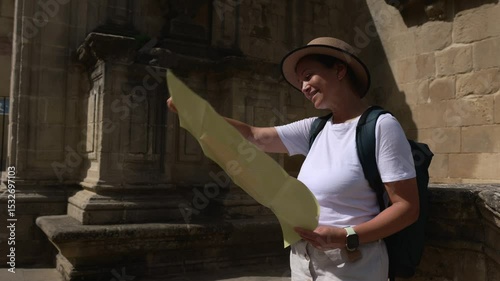 A Happy Woman Tourist Explores an Ancient Medieval European City, Using a Map to Discover New Historical Travel Destinations and Charming Old Streets While Enjoying Her Sunny Vacation.