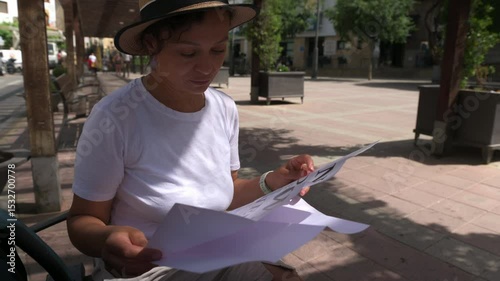 A woman tourist explores a historic city, discovering new travel destinations. She consults a map outdoors, planning to walk beautiful old streets and enjoy the charming town.