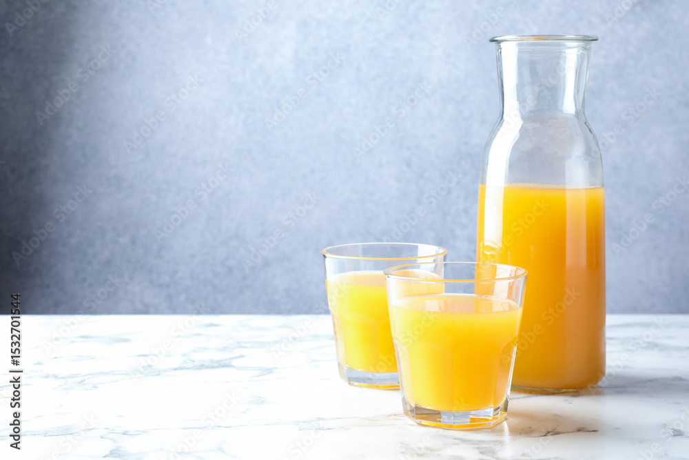 Tasty mango juice in glasses and carafe on white marble table, space for text Tasty mango juice in glasses and carafe on white marble table, space for text