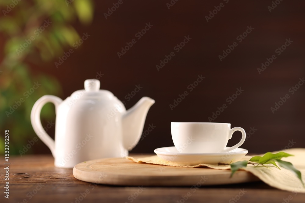 Fototapeta premium Cup of tasty tea, teapot and leaves on wooden table