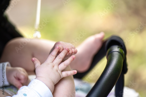 Baby in stroller demonstrates early development stage - hand-foot interaction, a precursor to crawling