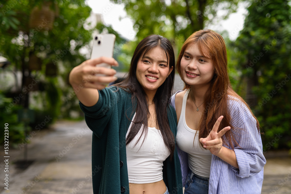 Fototapeta premium two young women talking on the phone in park