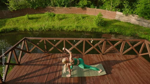 woman practicing yoga during sunrise on a terrace of a remote cabin in the woods with a lake view