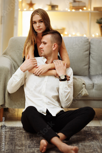 a girl in a black dress hugs the guy from behind, behind the neck and shoulders, care and love. date, valentines day