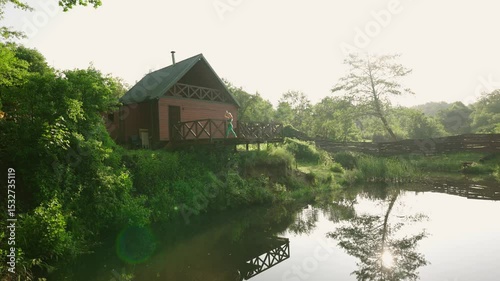 woman practicing yoga during sunrise on a terrace of a remote cabin in the woods with a lake view