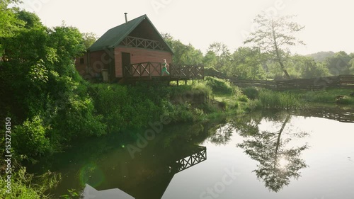 woman practicing yoga during sunrise on a terrace of a remote cabin in the woods with a lake view