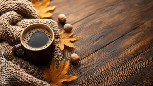 Warm cup of black coffee on a knitted blanket with autumn leaves and acorns on a rustic wooden surface, evoking cozy fall vibes