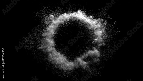 A grayscale image depicting a ring of white particulate matter exploding outwards against a pure black background, forming a circular void at its center