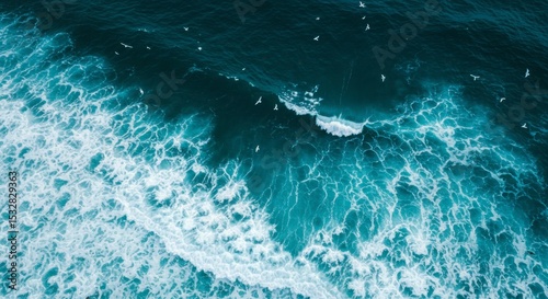 Aerial shot of ocean waves crashing, with a flock of birds flying above the foamy water