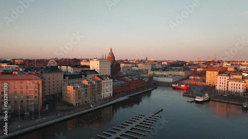 Aerial drone shot of the bay of Helsinki, Finland, at sunrise, with soft golden light reflecting on the calm Baltic Sea and the city slowly awakening