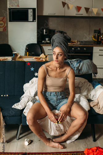 Photography Sad young woman sitting on sofa after party at home