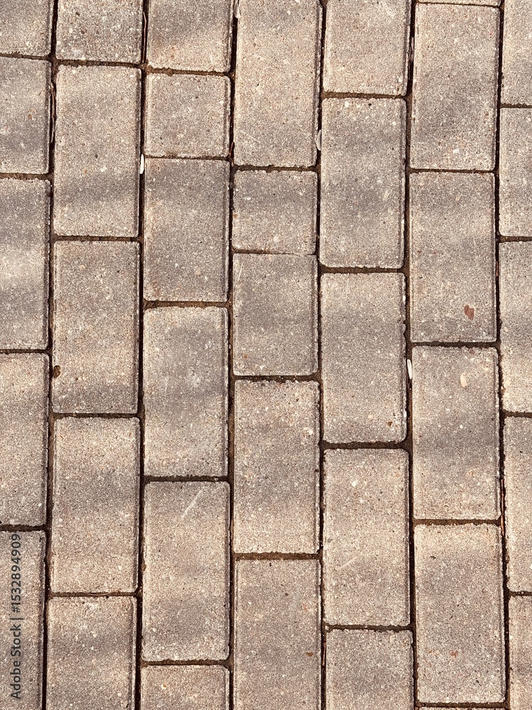 Obraz premium A detailed description of a Gray Paving Stones Pattern used in various outdoor settings. Clos-eup of modern gray paving stones, highlighting their intricate texture and careful arrangement