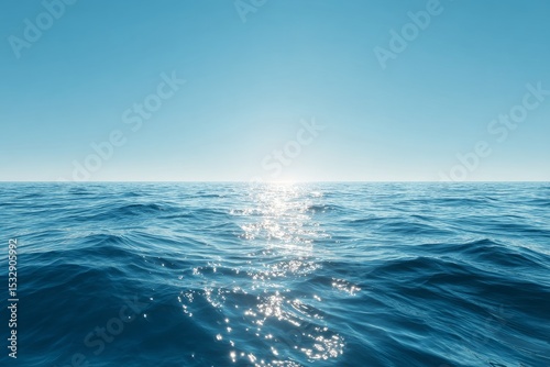 Tranquil ocean surface reflecting sunlight under clear blue sky  