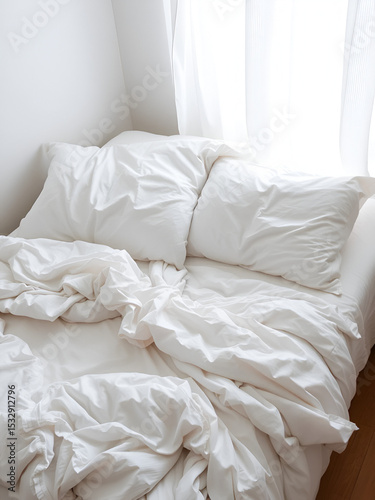 messy bed with white bedding sheets and pillows