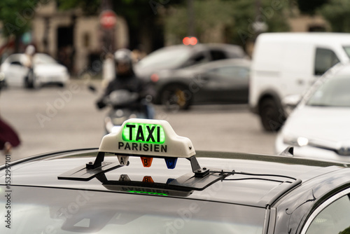 Fototapeta Naklejka Na Ścianę i Meble -  Green illuminated taxi sign on a Parisian cab, indicating availability for hire in the bustling city