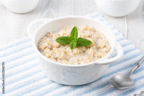 Oatmeal porridge in white bowl, close up view