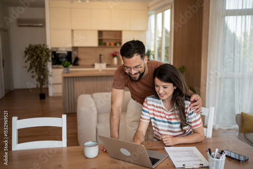 Φωτογραφία Happy couple doing finances and calculating bills at home using laptop