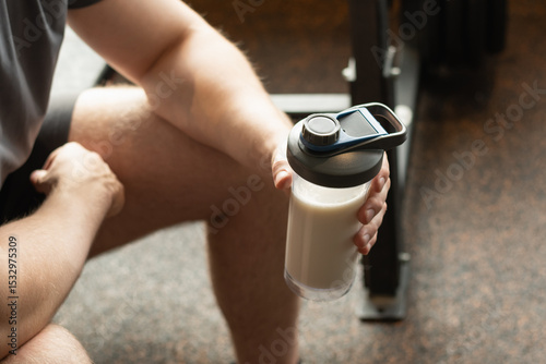 Close up shot of man at gym holding protein shaker. Bodybuilder during strength training. Fitness healthy lifestyle concept. Supplement product, creatine, glutamine for workout.