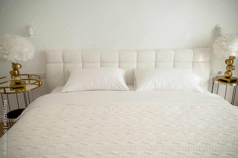 Obraz premium Bright bedroom with white pillows with a blanket and a plaid on the bed, a bedside table with a lamp