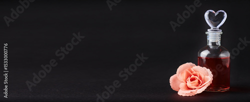 Artificial flower and a container of perfume on a black background with a copy space