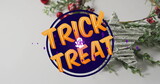 Displaying purple Trick or Treat sign on white tabletop, with wreath, berries and star ornament