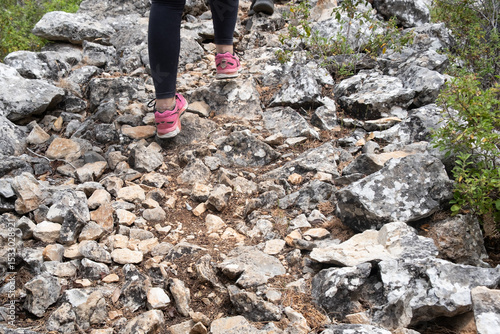 Woman hiking on rocky mountain trail wearing pink sneakers