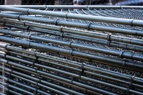 galvanized metal wire mesh fence panels stacked and ready for installation as a temporary barricade. industrial or construction design element or background. progress and site development