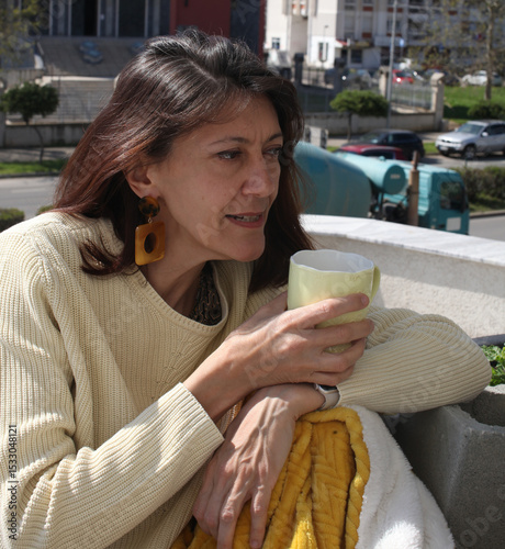 an adult woman on terrace making notes, working with phone