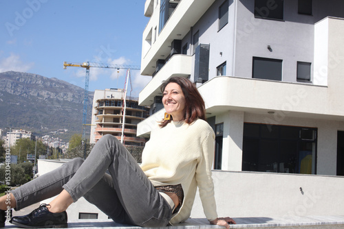 an adult woman on terrace making notes, working with phone