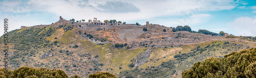 Scenic view of the ancient greek city of Pergamon in Turkey, featuring its well preserved ruins standing atop a lush green hill photo