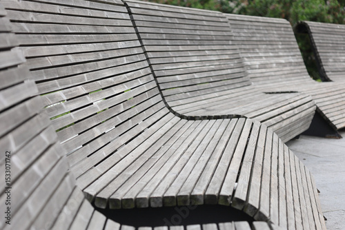 Row Of Modern Grey Wooden Park Benches With A Curved Slatted Design. Outdoor Public Seating. Perspective View.