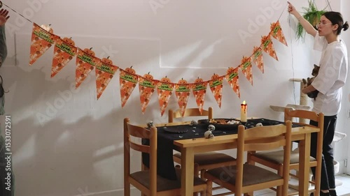 Three Caucasian sisters decorate the house with Halloween flags.