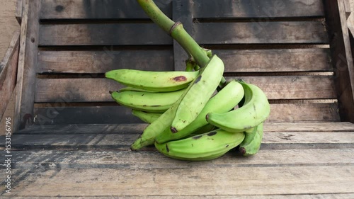 Fresh green plantain bunch on a rustic wooden crate showcasing tropical agriculture, healthy nutrition and organic produce.