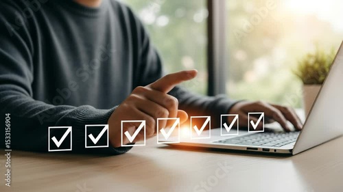 Person pointing at checklist on laptop screen with natural light in the background indoors