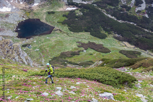 Adventure enthusiast hiking through dramatic rocky wilderness, using poles for stability while crossing steep terrain dotted with massive stones