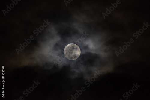 Full moon in the night sky with clouds. 