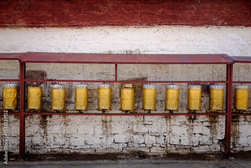 Fotografía Golden tibetan prayer wheels along a temple wall in Lhasa, Tibet