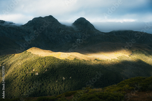 Evening light catching the side of mountains as clouds roll in.