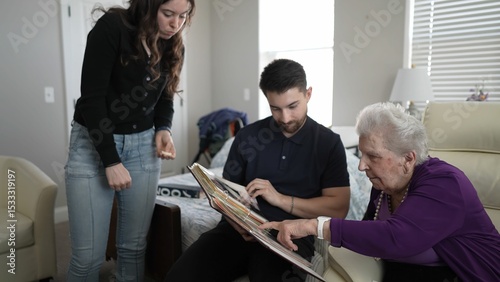 фотографія An elderly woman sits with her grandson and granddaughter, engaged in a heartfelt activity of reminiscing over a family album