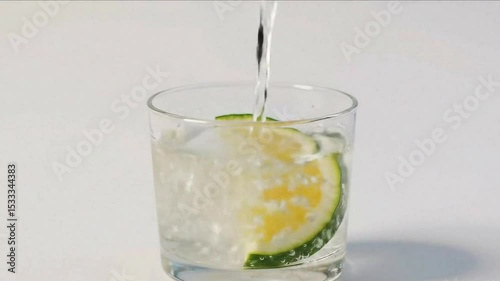 A clean, minimalist image of sparkling water being poured into a glass with a fresh lime slice and bubbles, set against a bright white background	