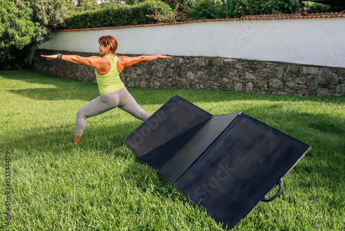 Woman doing yoga in garden with portable solar panels