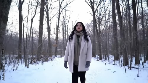 Young Woman Walking Through Snowy Forest in Winter Wearing Light Coat and Scarf in Calm Natural Setting