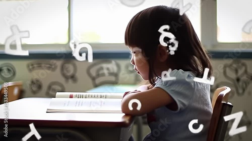 Young Girl Reading Book in Classroom Surrounded by Floating Letters