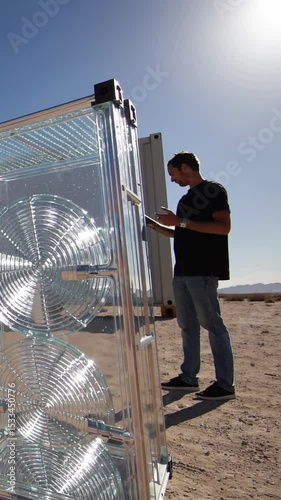 Vertical screen, professional engineer monitoring transparent solar panel performance using tablet in desert environment, showcasing renewable energy technology innovation photo