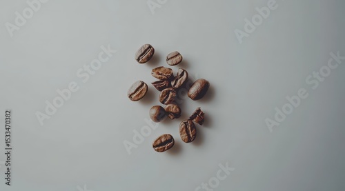 Scattered roasted coffee beans on a light gray surface, some split open, showing their inner texture