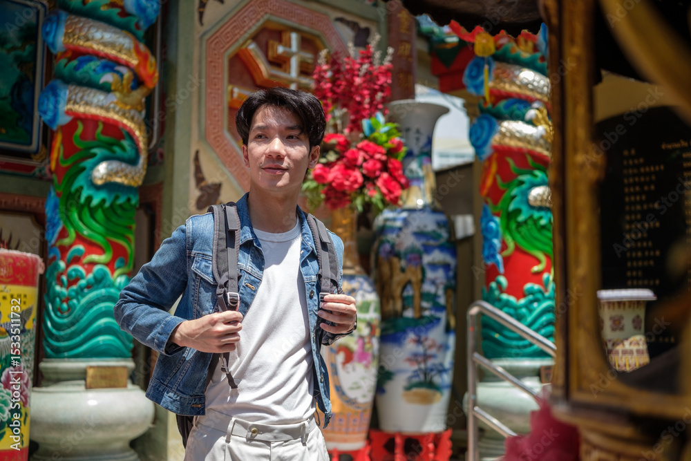 Obraz premium Traveler in denim jacket exploring a traditional religious shrine during a cultural trip.