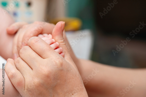 Mother's hands gently massaging a baby's feet to promote relaxation and healthy development